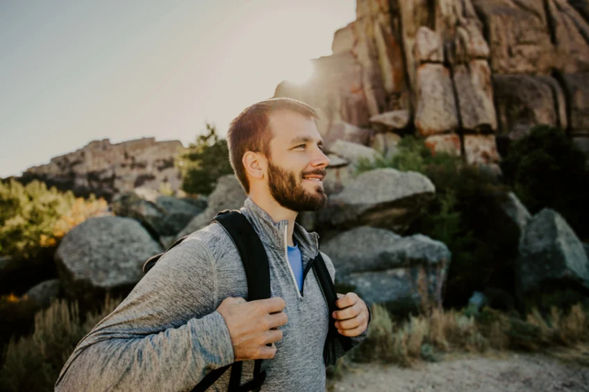 Man hiking with black backpack through shaded high desert canyon for adventure therapy