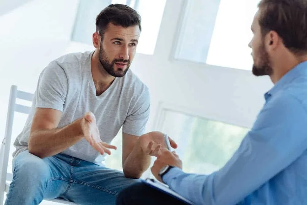 childhood-trauma Man describing childhood trauma to therapist near large window