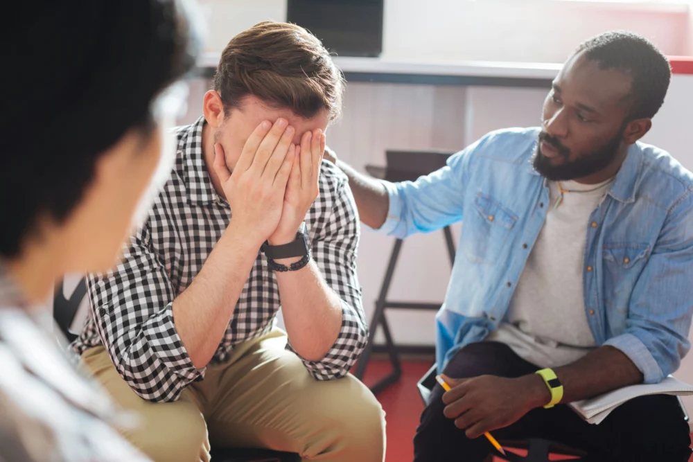 Frustrated man being comforted by another man in an addiction support group near Eagle, Idaho