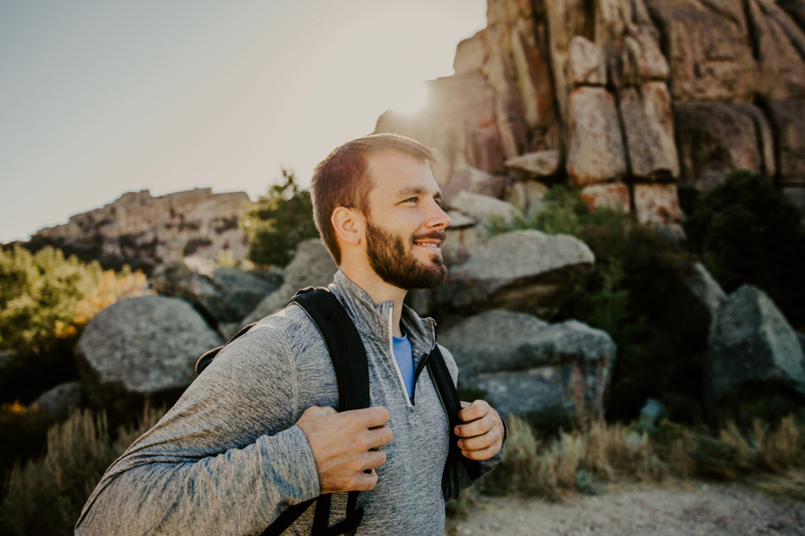 Man hiking with black backpack through shaded high desert canyon for adventure therapy