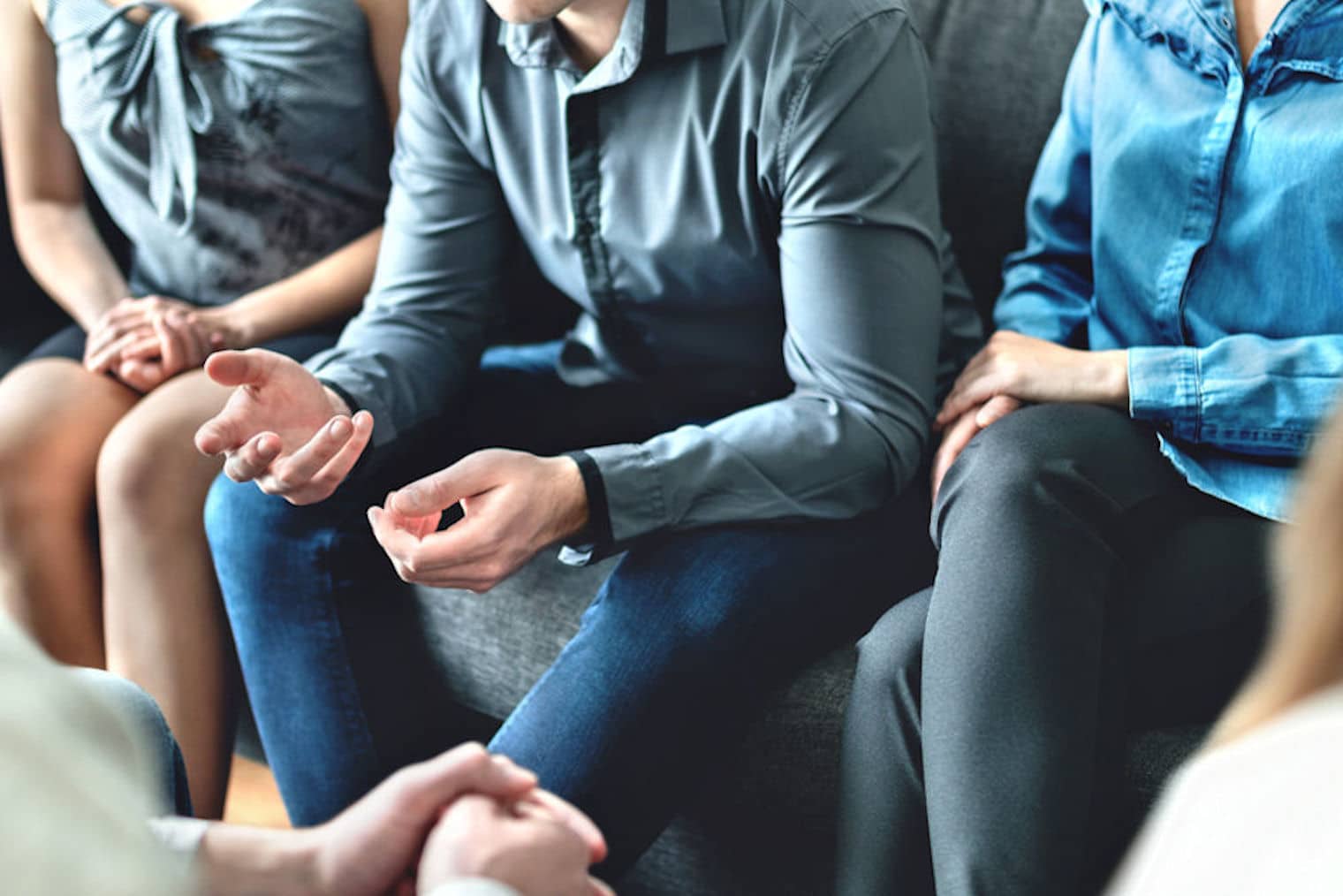 Mixed-gender addiction recovery group of people mostly wearing shades of grey and blue