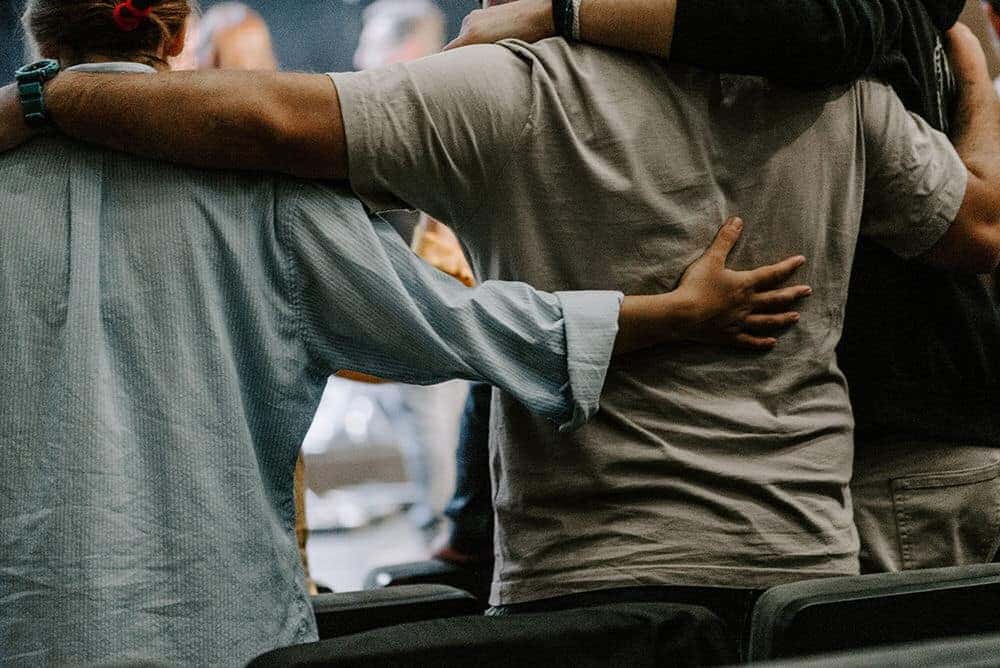 Rear view of men in circle embracing each other's sides