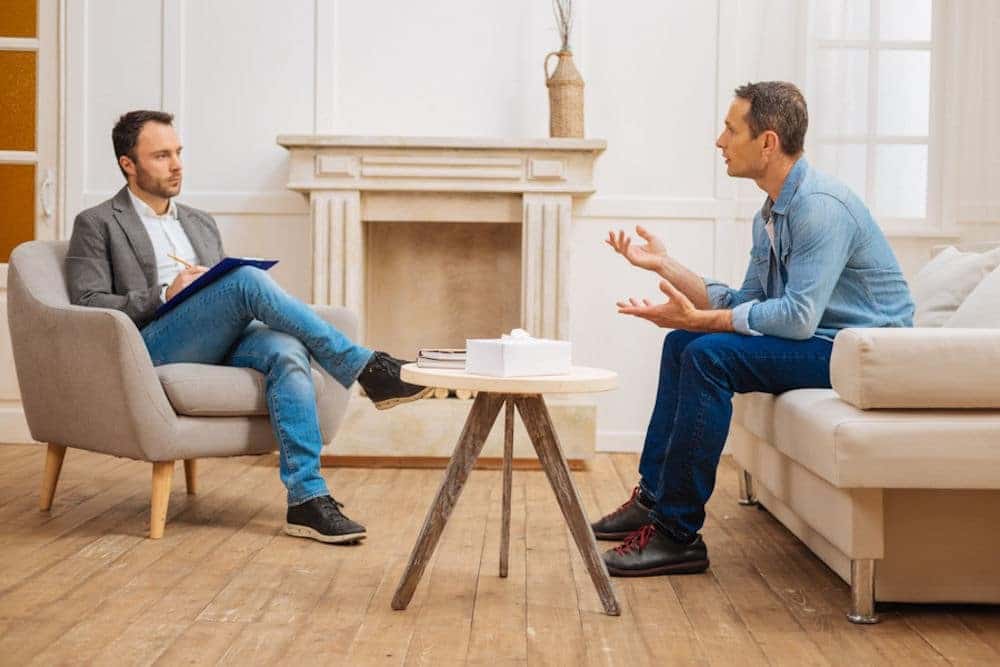 Man talking to therapist about cannabis in beige office and depression