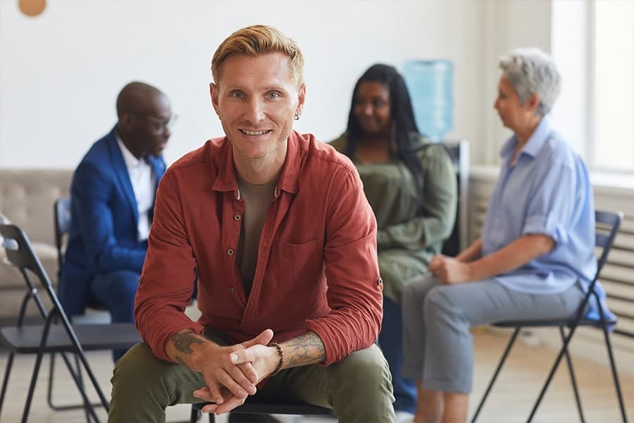 Cheerful man in red shirt looking out from four-person mixed gender fentanyl addiction support group