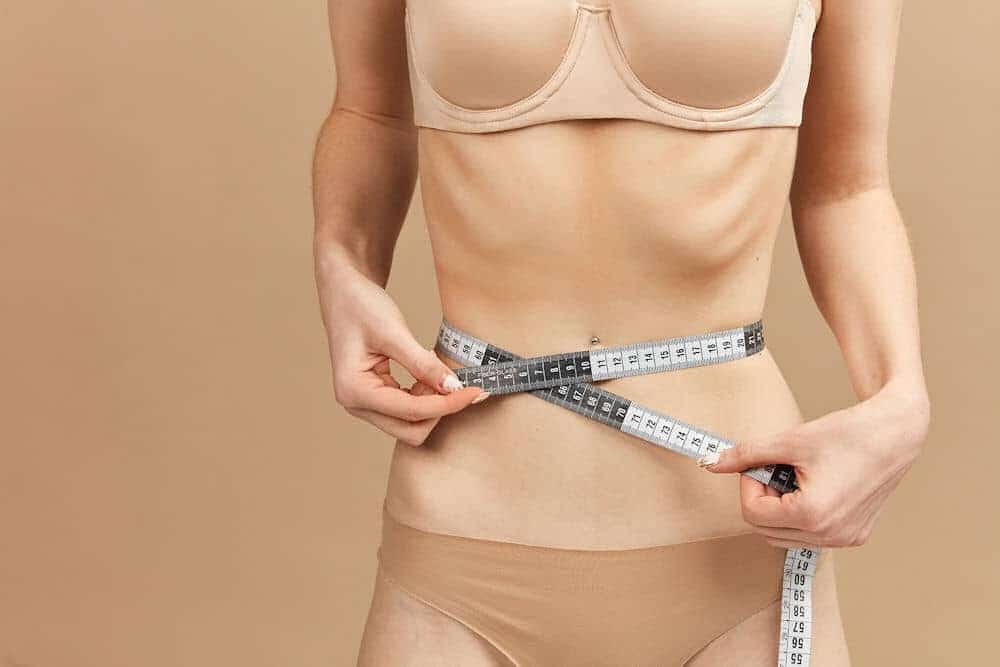 thin woman measuring her waist