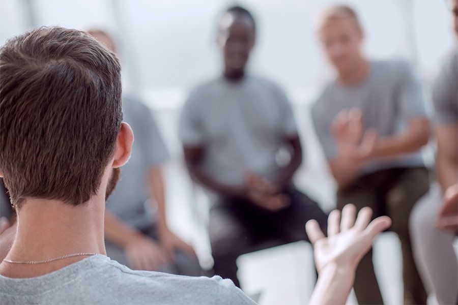 Man asking people in addiction recovery group about long-term recovery