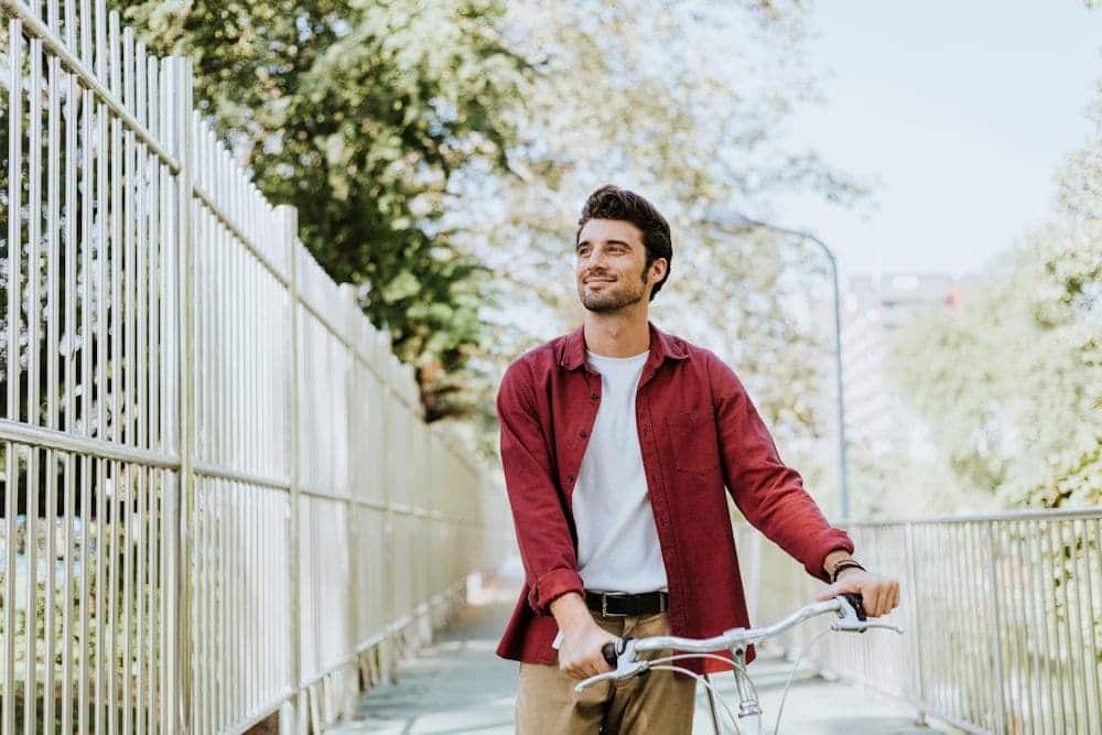 Happy man walking bicycle outside