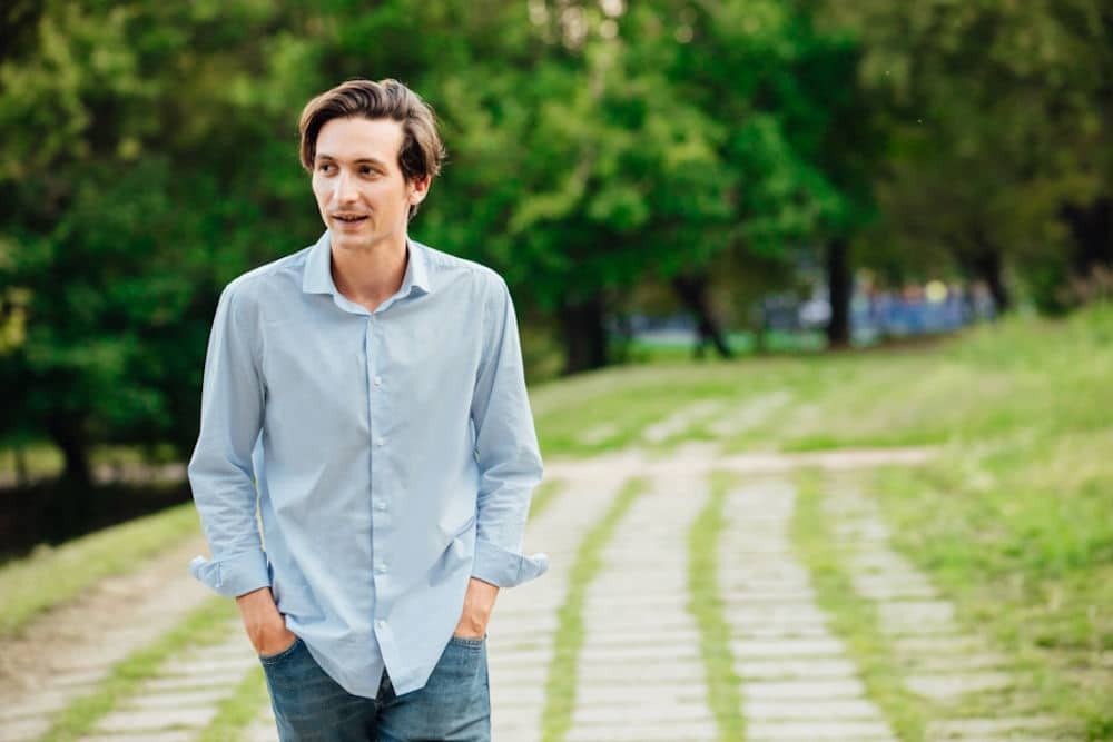 Man answering question while walking down mossy trail path