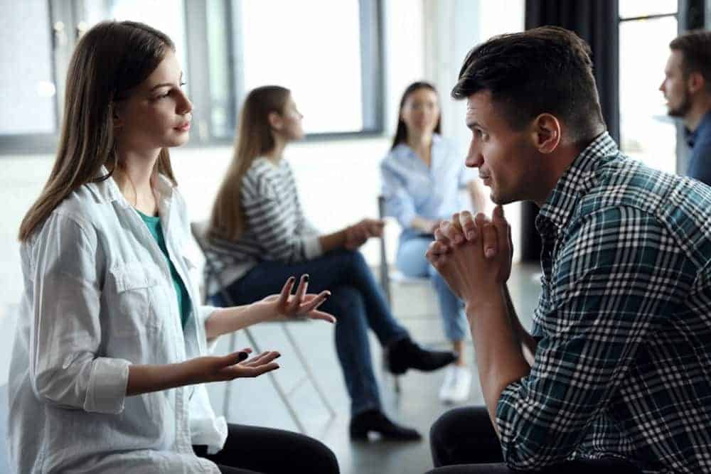 Young man listens while woman describes stress in therapeutic setting