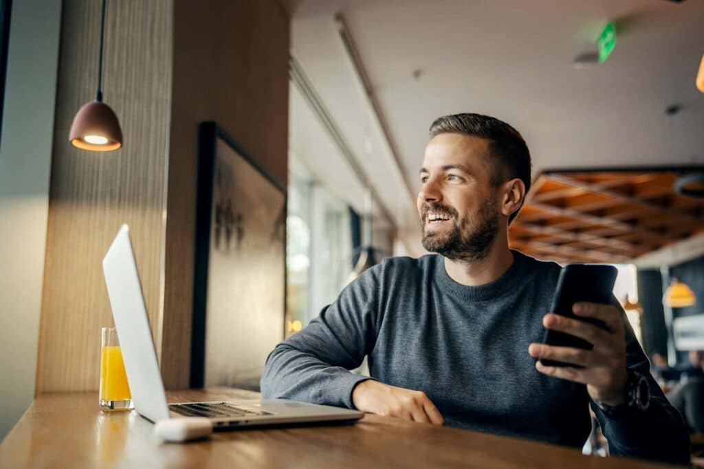 Middle-aged man researching pink cocaine on laptop and smartphone