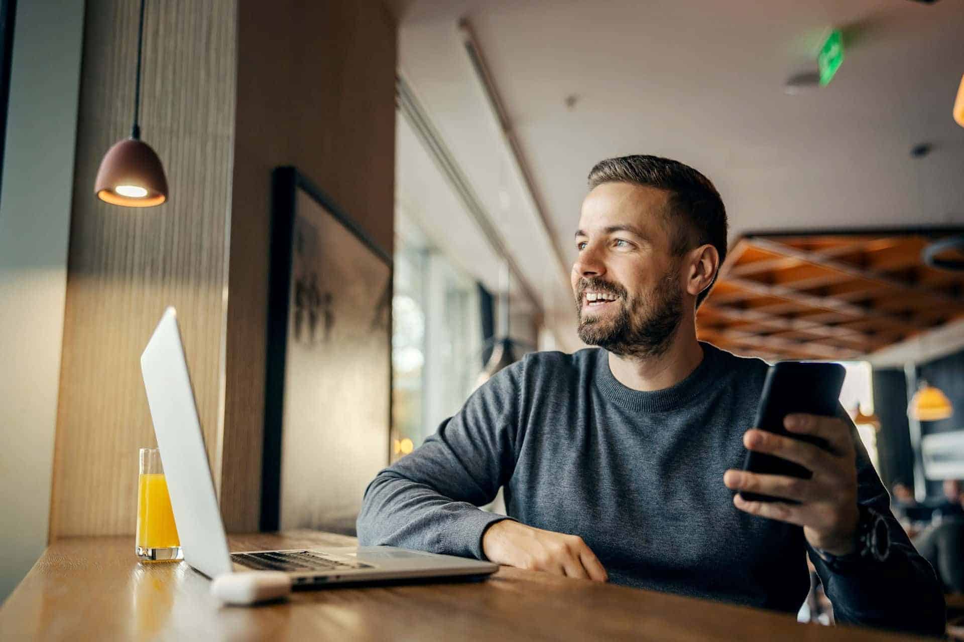 Middle-aged man researching pink cocaine on laptop and smartphone