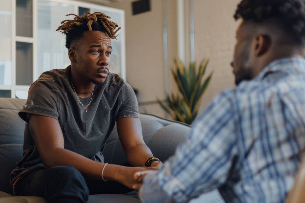 Anxious man wrapping arms over bent head.
