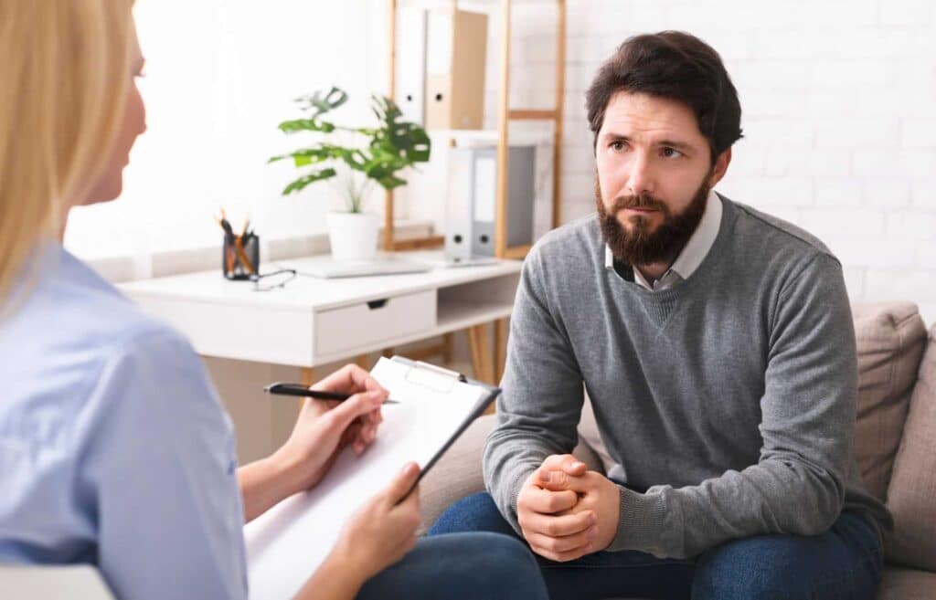 Grieving man looking unsure when talking to therapist