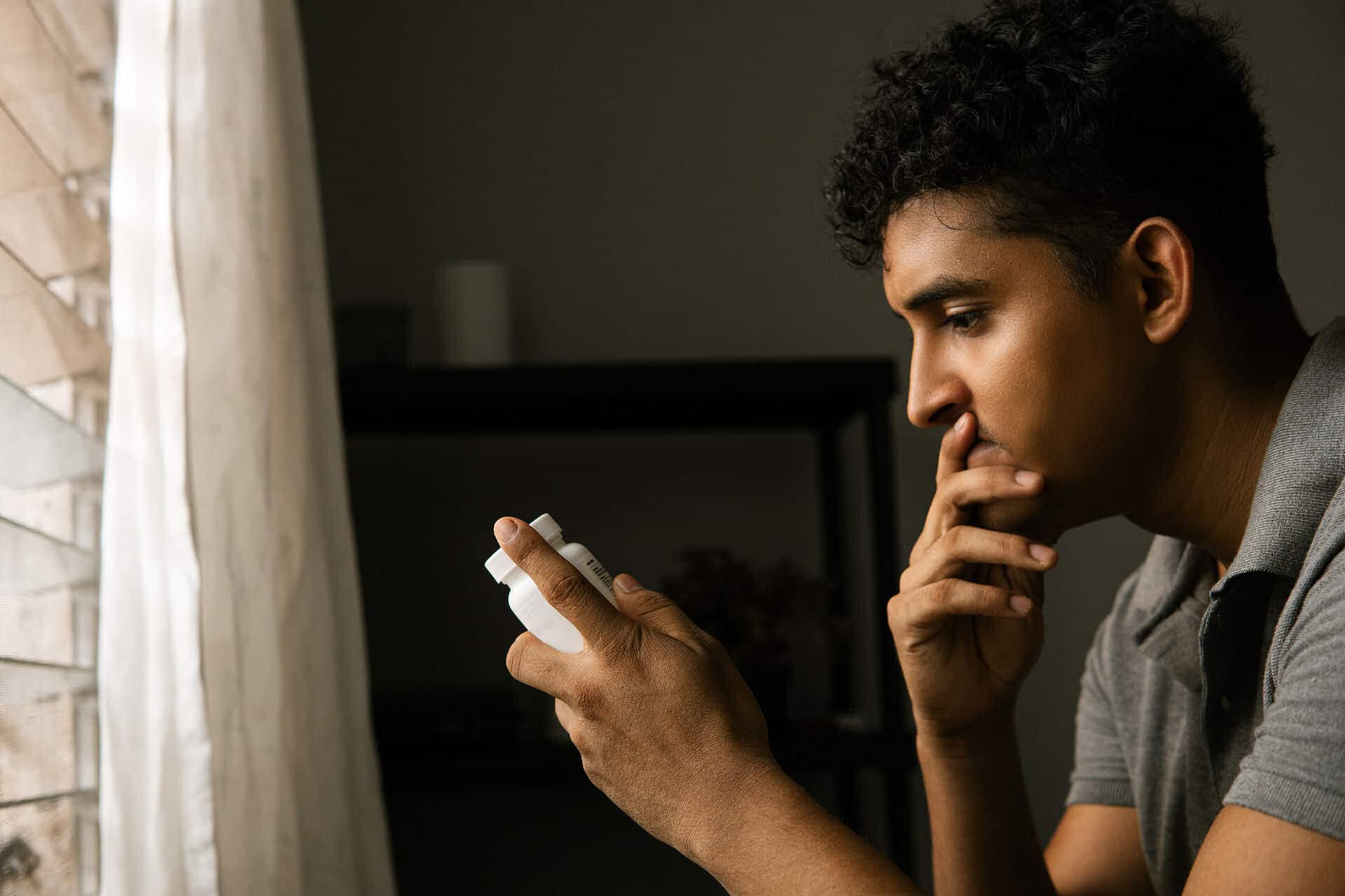 Man looks at opioid bottle while considering it