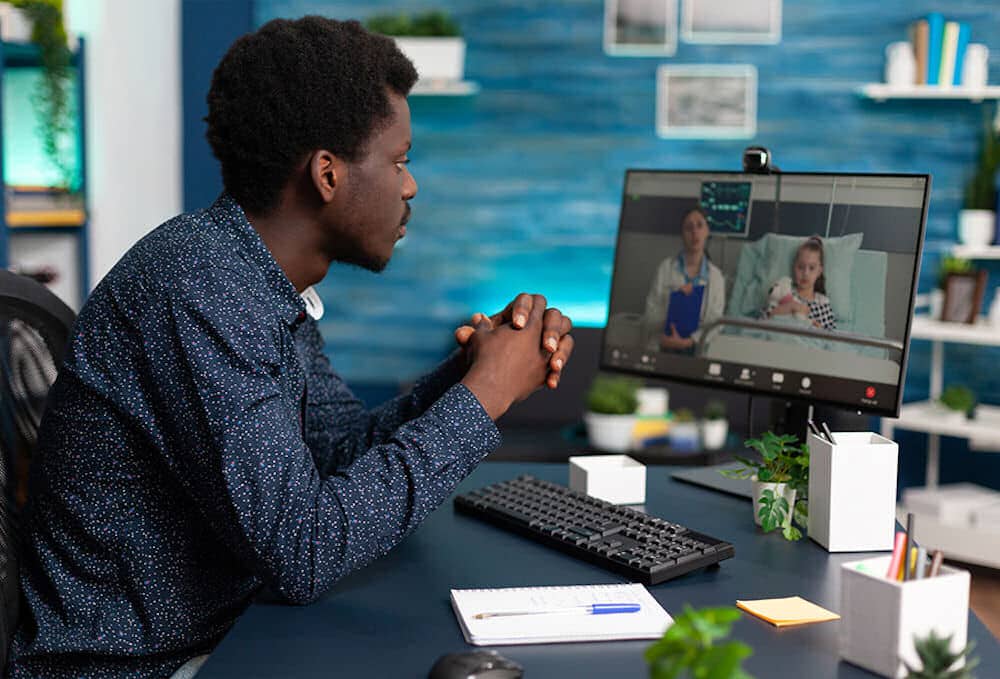 Man attending teleheath medical appointment at desktop computer