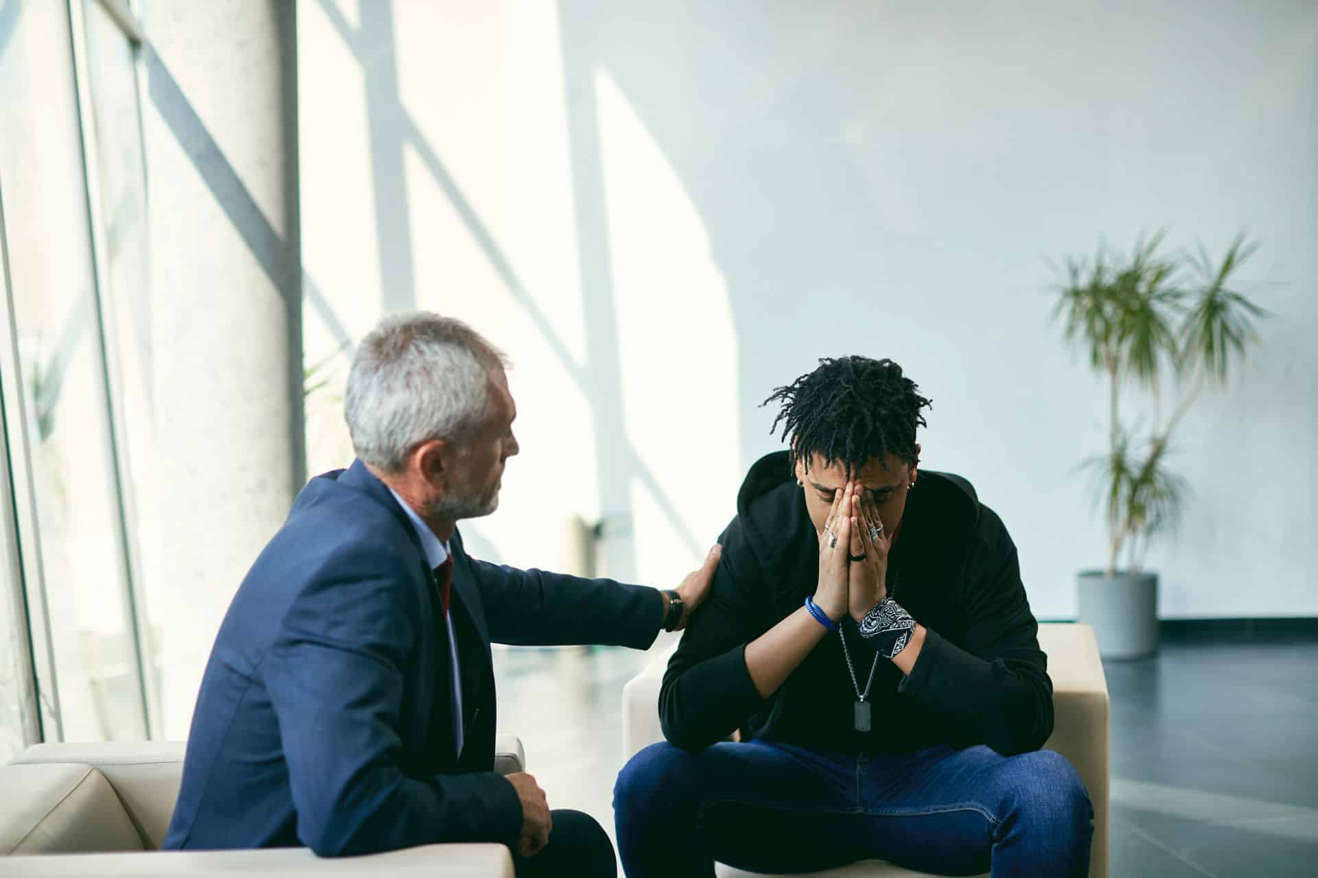 Older man comforting younger man as he describes body image issues.