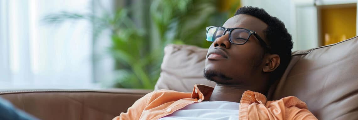 Man with glasses leaning back on couch with eyes closed