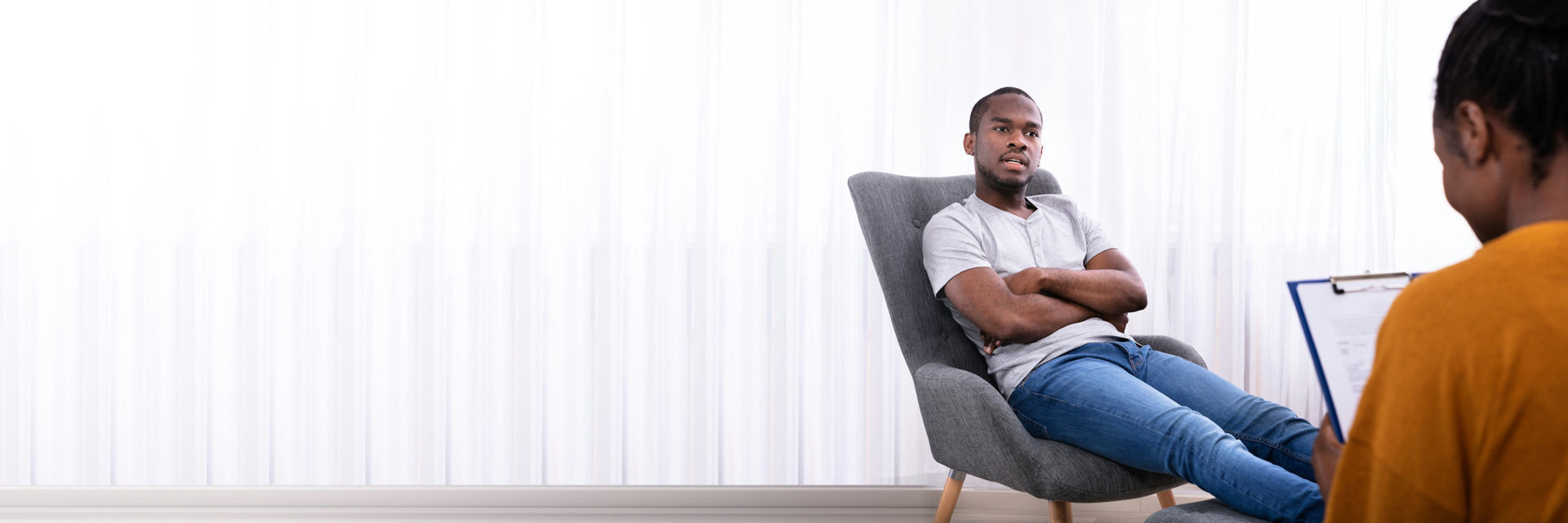 Skeptical man sitting with crossed arms while talking to therapist