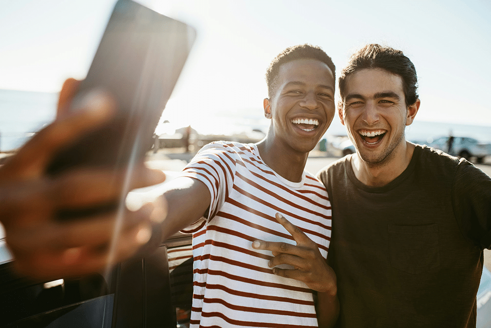 Two young men posing for a selfie on dock during golden hour.