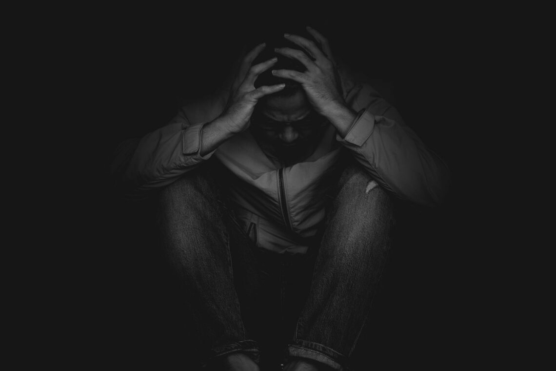 Black and greyscale picture of a man holding his head down after taking an 8-ball.