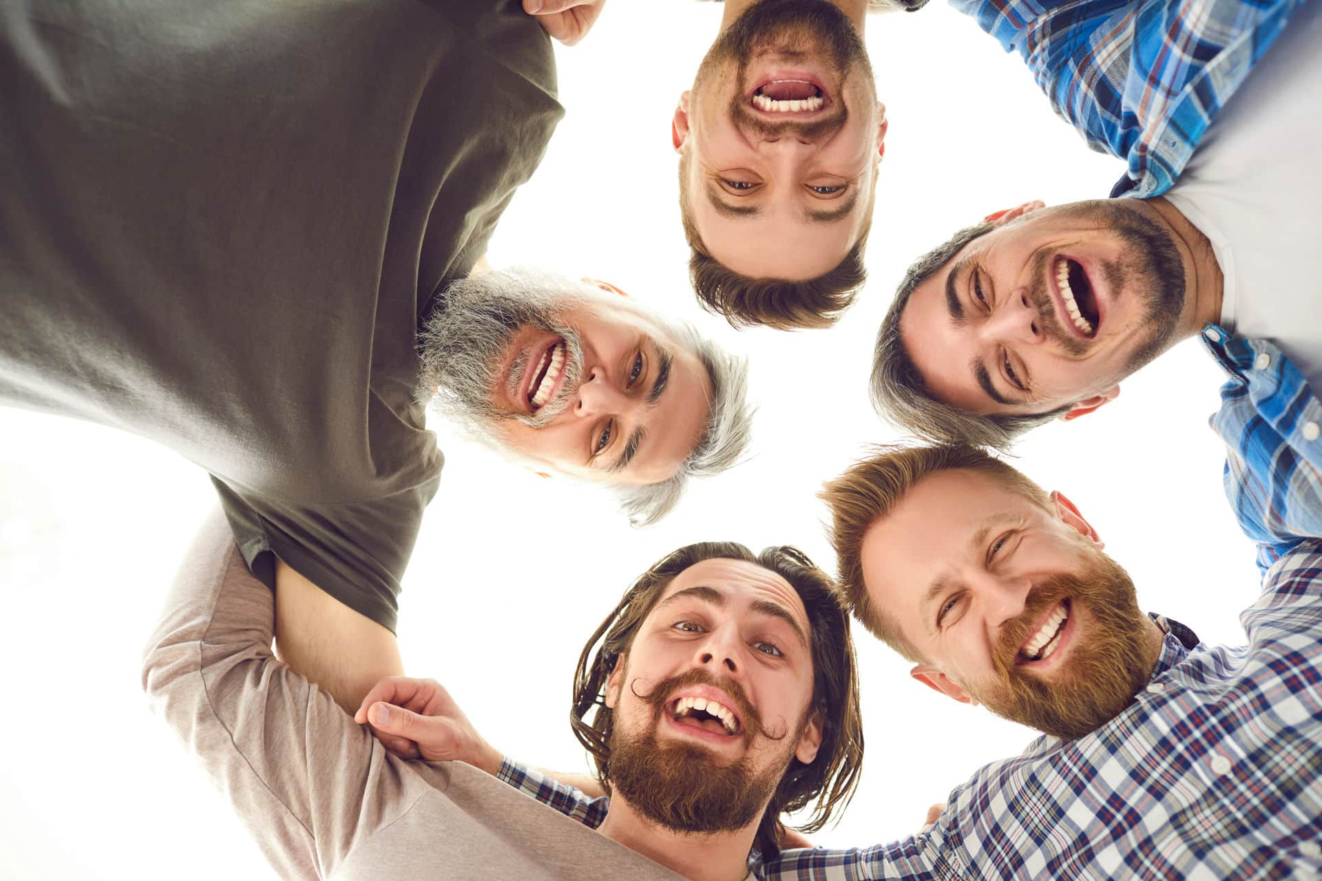Circle of men looking down after learning about chemsex in addiction recovery.